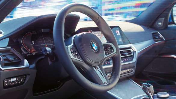 BMW 3 serijos sedanas, kintantis sportinis vairavimas. BMW 3 serijos sedano salono vaizdas iš šono sukoncentruotas į vairą su kintančio sportinio vairavimo sistema.