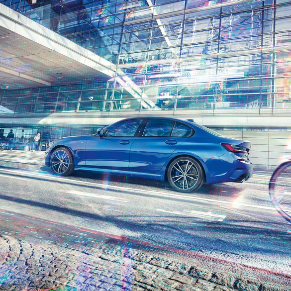 BMW 3 serijos sedanas, vaizdas iš šono. Prie stiklinio pastato stovinčio BMW 3 serijos sedano vaizdas iš šono dieną