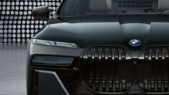 Akį traukiantis BMW M760e xDrive sedano G70 priekinės dalies dizainas Variklio dangtis ir priekinės grotelės su M logotipu, BMW M760e xDrive sedanas G70 BMW Individual dviejų atspalvių Black Sapphire metalizuota dažų apdaila BMW Individual Dravite Grey pilka metalizuota spalva vaizdas iš arti