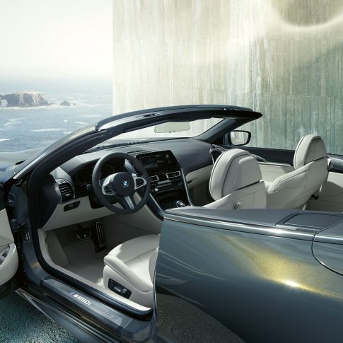 BMW M850i xDrive kabrioletas, interjeras. BMW M850i xDrive kabrioletas Dravit Grey pilko metaliko spalvos su atviru minkštu stogu, interjeras su M odiniu vairu ir BMW Individual Merino Ivory White dramblio kaulos spalvos odos apdaila.