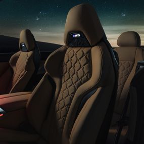 Merino odos M sportinės sėdynės. BMW M8 Competition kabrioletas su atviru minkštu stogu po žvaigždėtu dangumi, interjeras su M sportinėmis Merino odos sėdynėmis ir raudonu aplinkos apšvietimu.