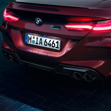 BMW M8 Competition kabrioletas, priartintas vaizdas iš galo. BMW M8 Competition kabrioletas Motegi Red raudono metaliko spalvos, priartintas LED galinių žibintų ir M8 Competiton ženklelio vaizdas iš arti.