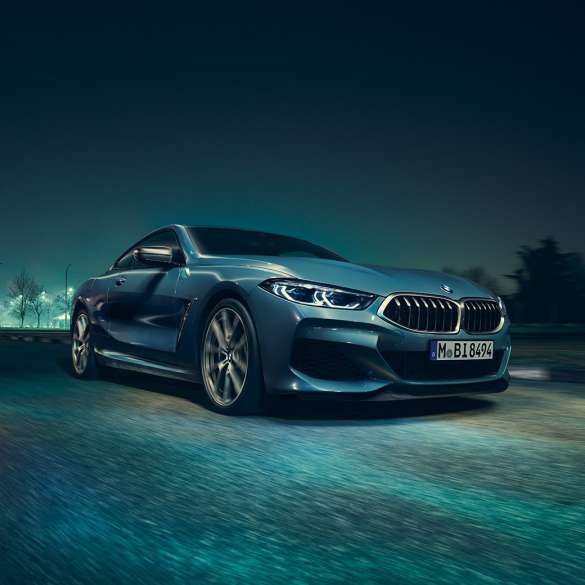 BMW M850i xDrive kupė, trijų ketvirčių vaizdas iš kairės priekinės pusės BMW M850i xDrive kupė Barcelona Blue mėlyno metaliko spalvos, trijų ketvirčių naktį važiuojančio automobilio vaizdas iš kairės priekinės pusės