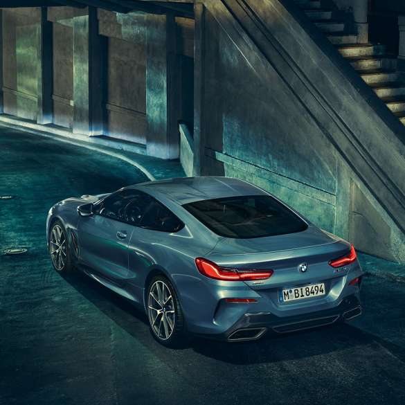 BMW M850i xDrive kupė, trijų ketvirčių vaizdas iš galinės kairės pusės BMW M850i xDrive kupė Barcelona Blue mėlyno metaliko spalvos, trijų ketvirčių naktį stovinčio automobilio vaizdas iš galinės kairės pusės