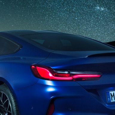 M galinis aptakas BMW M8 Competition kupė Marina Bay Blue mėlyno metaliko spalvos, M Carbon galinio aptako vaizdas naktį iš arti