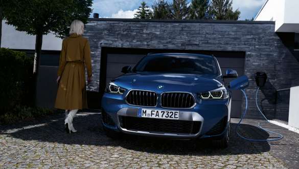 Įkraunamo hibridinio BMW X2 xDrive25e (F39) vaizdas iš priekio garažo fone Įkraunamo hibridinio BMW X2 xDrive25e (F39) vaizdas iš priekio garažo fone su modeliu