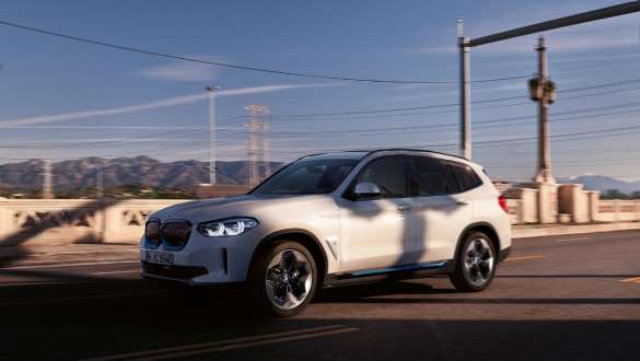 Adaptyvioji M pakaba, gatvėje stovintis BMW iX3 G08 Adaptyvioji M pakaba, BMW iX3 G08 2020, balto Mineral White metaliko spalvos, gatve važiuojančio automobilio trijų ketvirčių vaizdas iš priekio