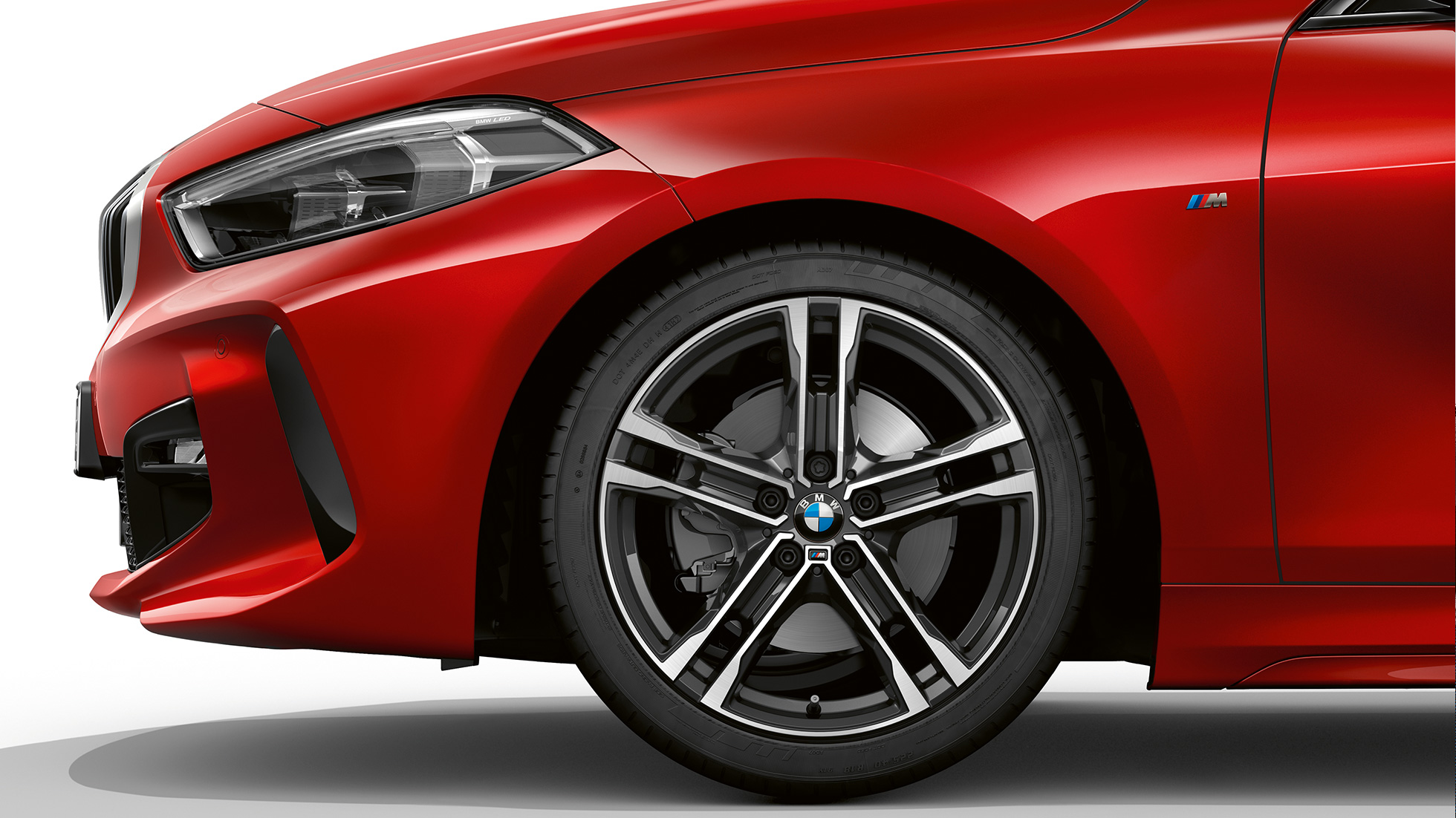 BMW 1 serijos modelis M Sport, priekinis vaizdas iš šono Melbourne Red raudono metaliko spalvos BMW 1 serijos modelis M Sport, priekinis vaizdas iš šono su dvispalviais 17 colių M lengvojo lydinio ratlankiais „Double-spoke 550 M style“
