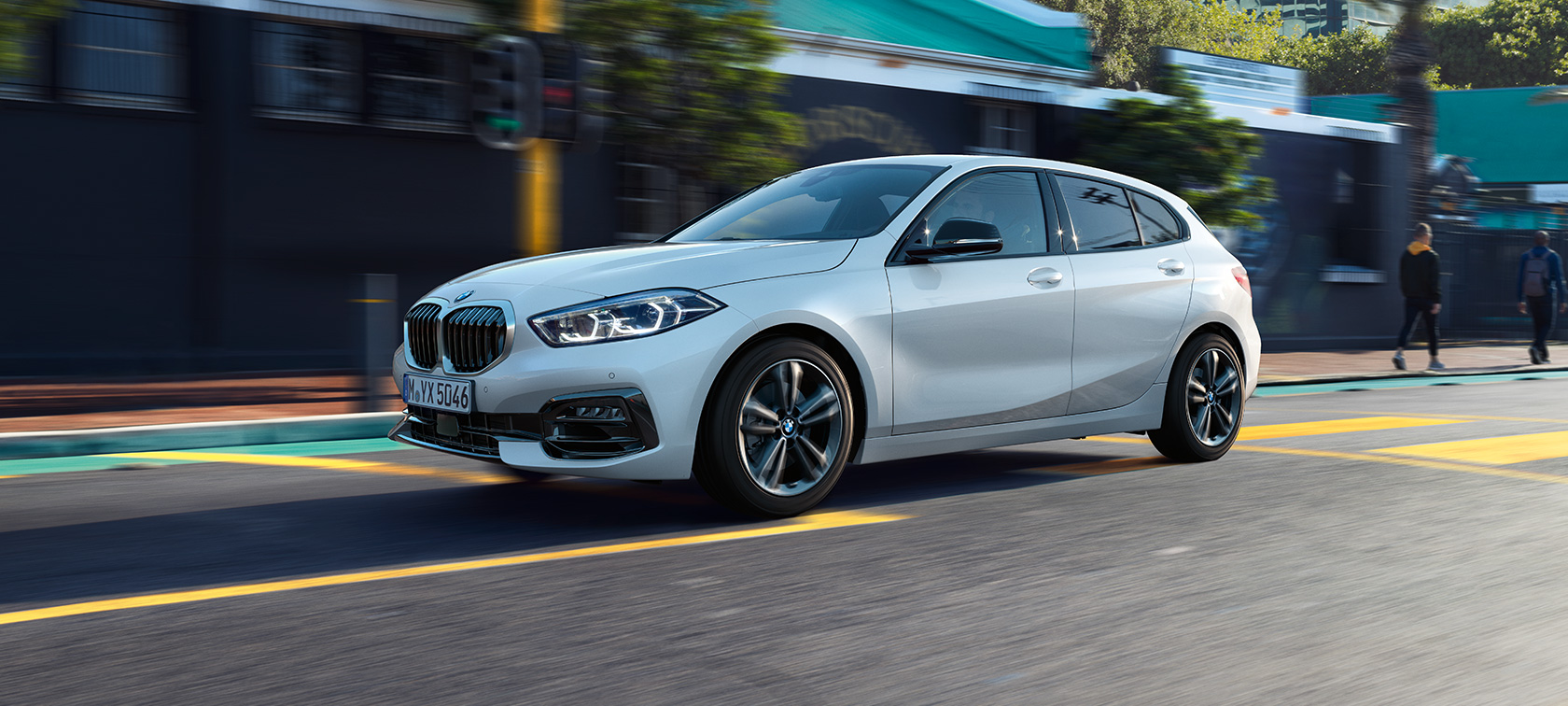 BMW 1 serijos modelio Sport Line, trijų ketvirčių vaizdas iš šono Mineral White balto metaliko spalvos BMW 1 serijos modelio Sport Line,keliu važiuojančio automobilio trijų ketvirčių vaizdas iš šono