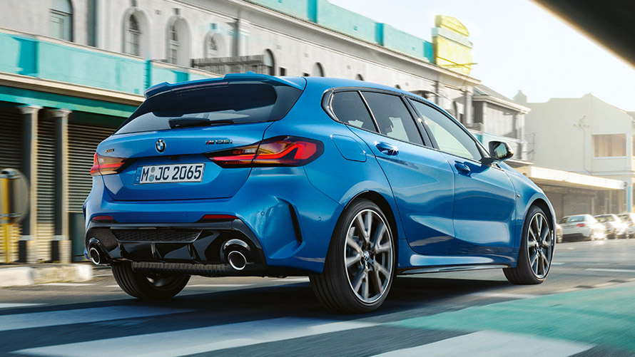 BMW 1 serijos (F40), važiuojančio automobilio trijų ketvirčių vaizdas iš galo BMW 1 serijos (F40) mėlynos metalizuotos <i>Misano Blue</i> spalvos, važiuojančio automobilio trijų ketvirčių vaizdas iš galo