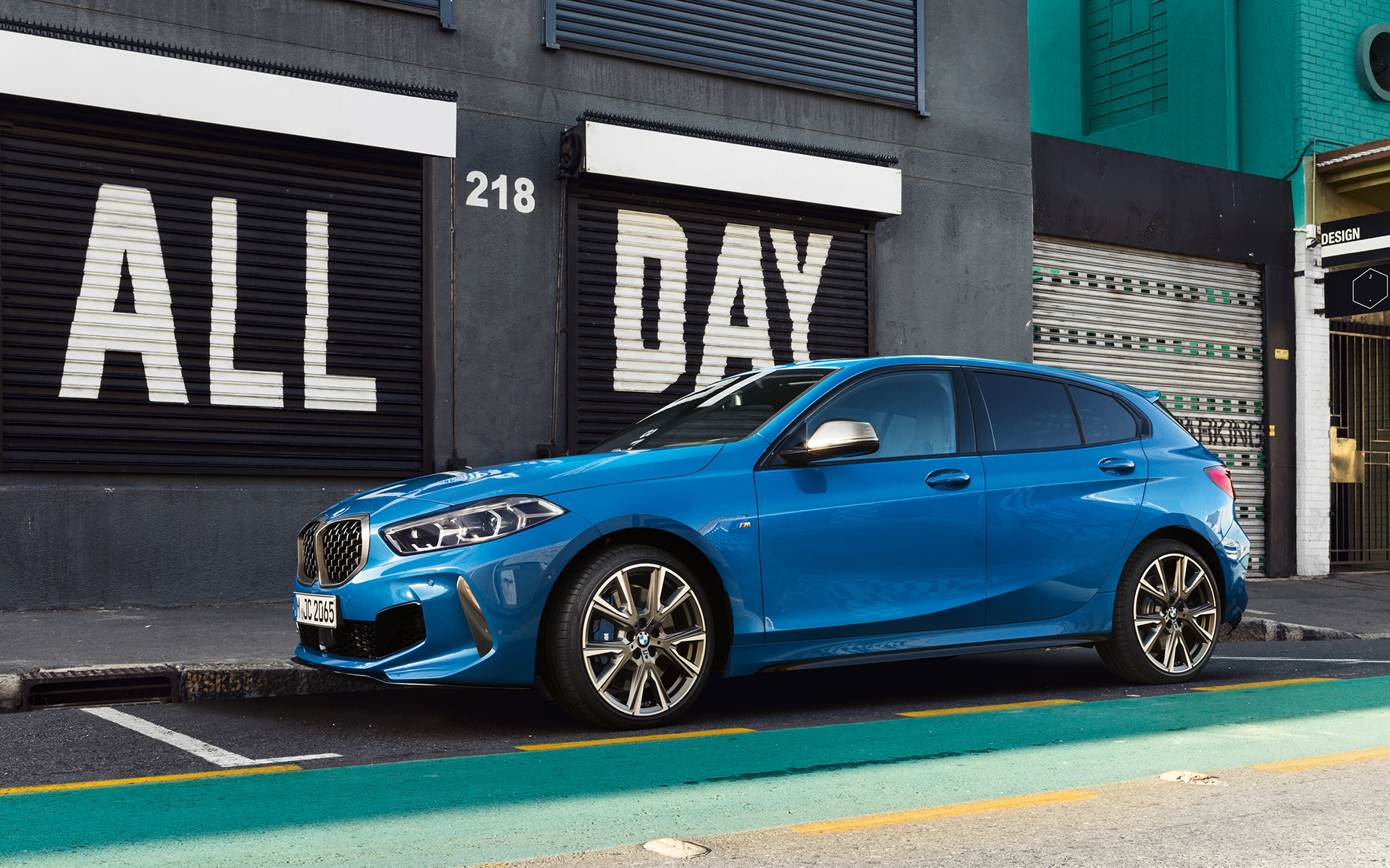 BMW 1 serijos M135i F40 stovėjimo aikštelėje BMW 1 serijos M135i F40 mėlynos metalizuotos Misano Blue spalvos, vaizdas iš šono stovėjimo aikštelėje