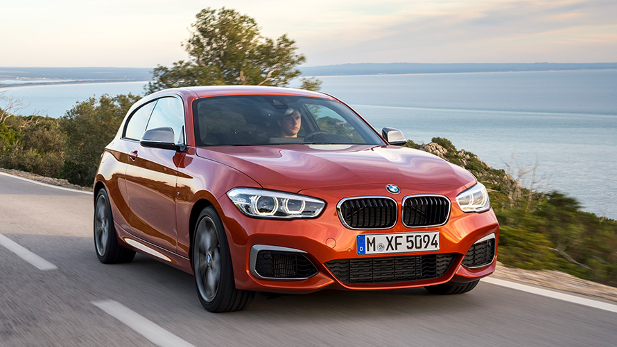 BMW M135i (F21) ežero ir kalnų fone važiuojančio automobilio trijų ketvirčių vaizdas priekio BMW M135i (F21) ežero ir kalnų fone važiuojančio automobilio trijų ketvirčių vaizdas priekio