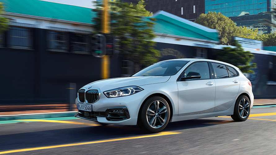 BMW 1 serija (F40) miesto fone važiuojančio automobilio trijų ketvirčių vaizdas iš šono BMW 1 serija (F40) miesto fone važiuojančio automobilio trijų ketvirčių vaizdas iš šono