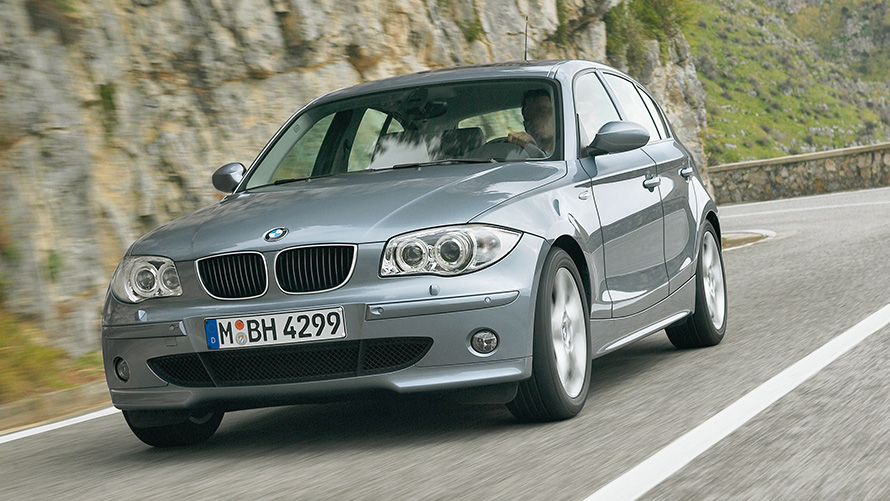 BMW 1 serija (E87) kalvų fone važiuojančio automobilio trijų ketvirčių vaizdas iš priekio BMW 1 serija (E87) kalvų fone važiuojančio automobilio trijų ketvirčių vaizdas iš priekio