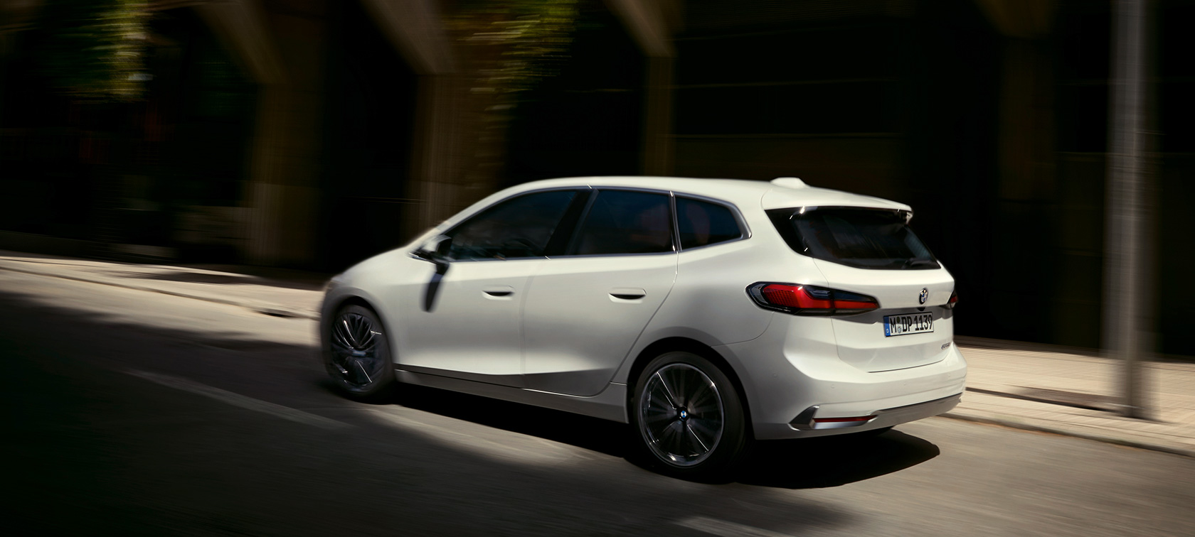 BMW 2 serijos Active Tourer (U06) 2021 metalizuotos baltos Mineral White spalvos, važiuojančio automobilio trijų ketvirčių vaizdas iš galo