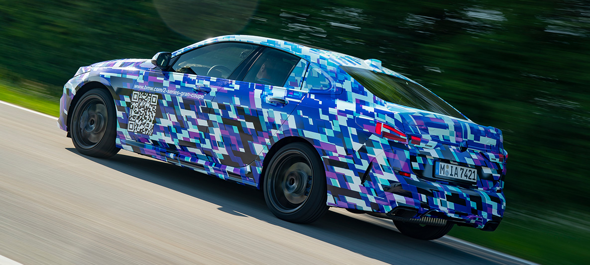 BMW 2 serijos Gran kupė vairavimo dinamika BMW 2 serijos Gran kupė F44, BMW M235i xDrive sportiškai važiuojantis keliu, užmaskuoto prototipo eksterjero trijų ketvirčių vaizdas iš šono