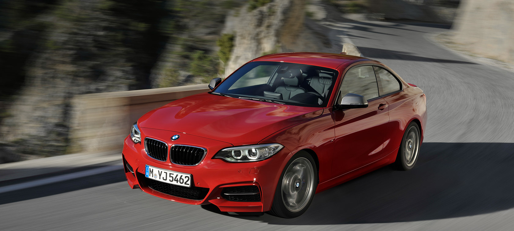 Gamtovaizdžio fone keliu važiuojančio BMW 2 serijos modelio trijų ketvirčių vaizdas iš priekio Gamtovaizdžio fone keliu važiuojančio BMW 2 serijos modelio trijų ketvirčių vaizdas iš priekioo