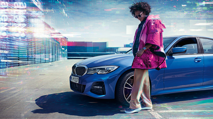 BMW 3 serijos sedanas (G20), mėlynos <i>Portimao Blue</i> metalizuotos spalvos, 7/8 vaizdas iš priekio BMW 3 serijos sedanas (G20), mėlynos <i>Portimao Blue</i> metalizuotos spalvos, 7/8 vaizdas iš priekio parkavimo aikštelėje su žmogumi pirmame plane
