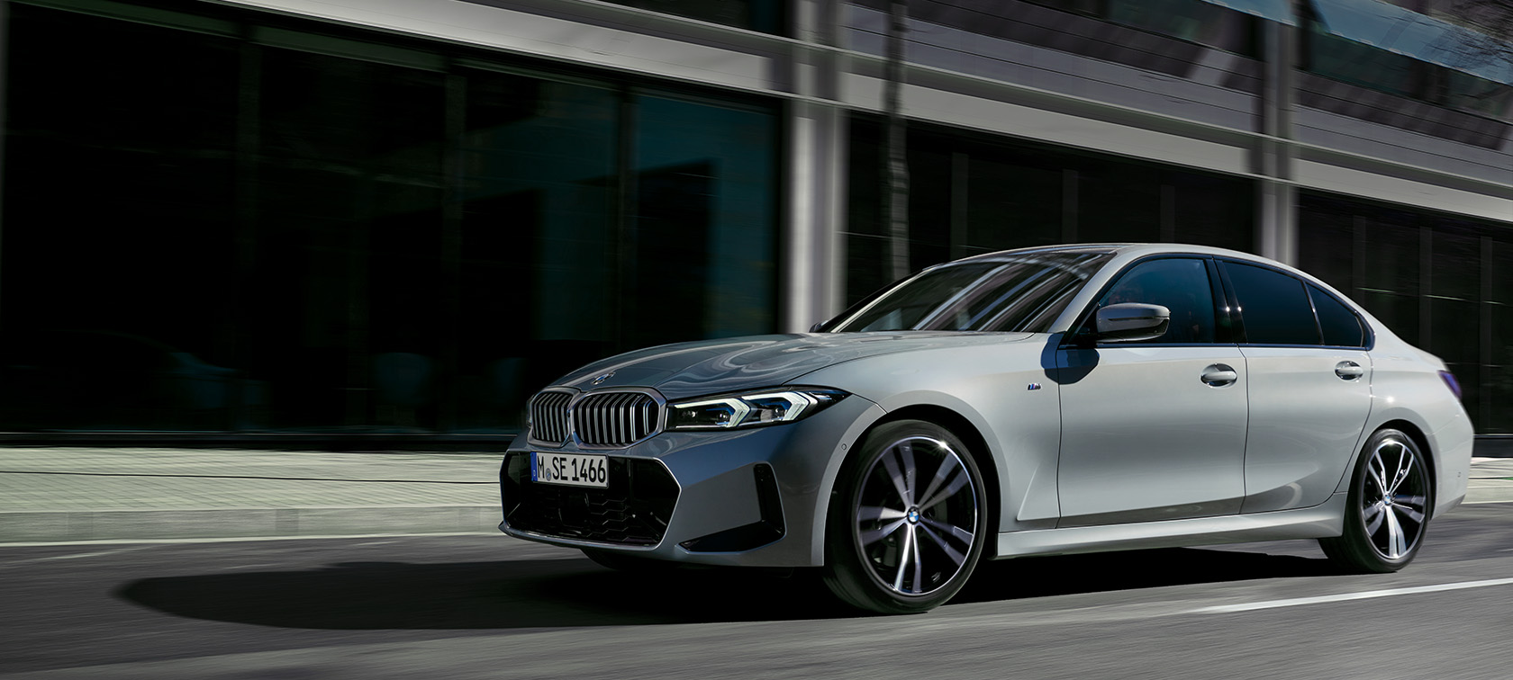 Sienos fone stovinčio BMW 3 serijos sedano LCI G20 pilkos Brooklyn Grey spalvos vaizdas iš šono