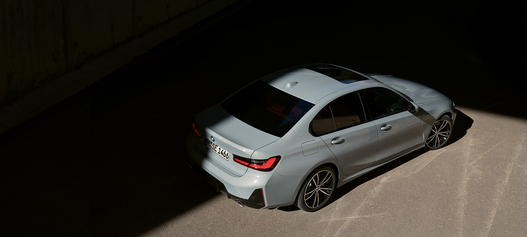 Stovinčio pilkos Brooklyn Grey spalvos BMW 3 serijos sedano LCI G20 trijų ketvirčių galinis vaizdas iš paukščio skrydžio Stovinčio BMW 3 serijos sedano LCI G20 trijų ketvirčių galinis vaizdas iš paukščio skrydžio