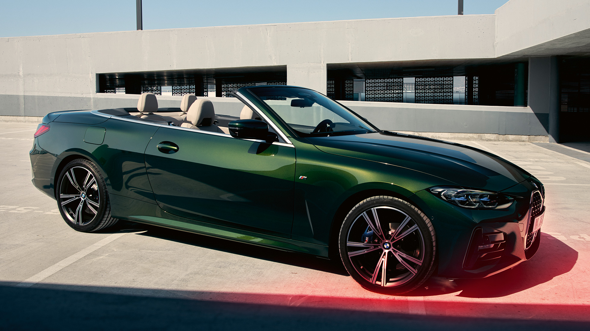 Trijų ketvirčių vaizdas iš priekio, BMW 4 serijos kabrioletas G23 2020 su šalia stovinčiu vyru BMW 4 serijos kabrioletas G23 2020 žalios „Sanremo Green“ metaliko spalvos, trijų ketvirčių vaizdas iš priekio su su šalia stovinčiu vyru