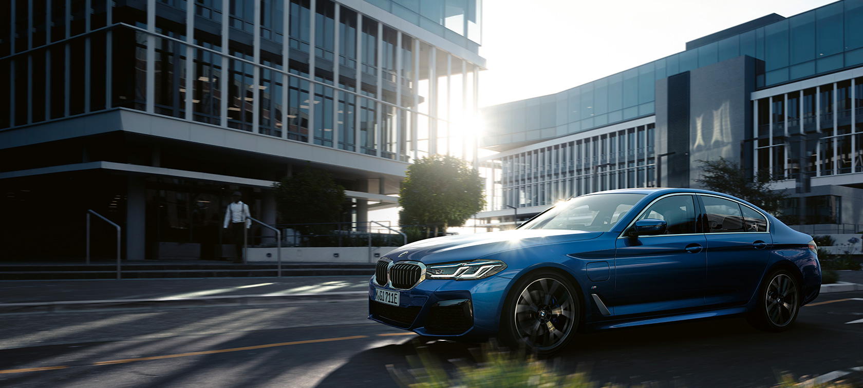 BMW 5 serijos sedanas G30 Facelift 2020 mėlynos Phytonic Blue spalvos važiuojančio automobilio trijų ketvirčių vaizdas iš priekio.