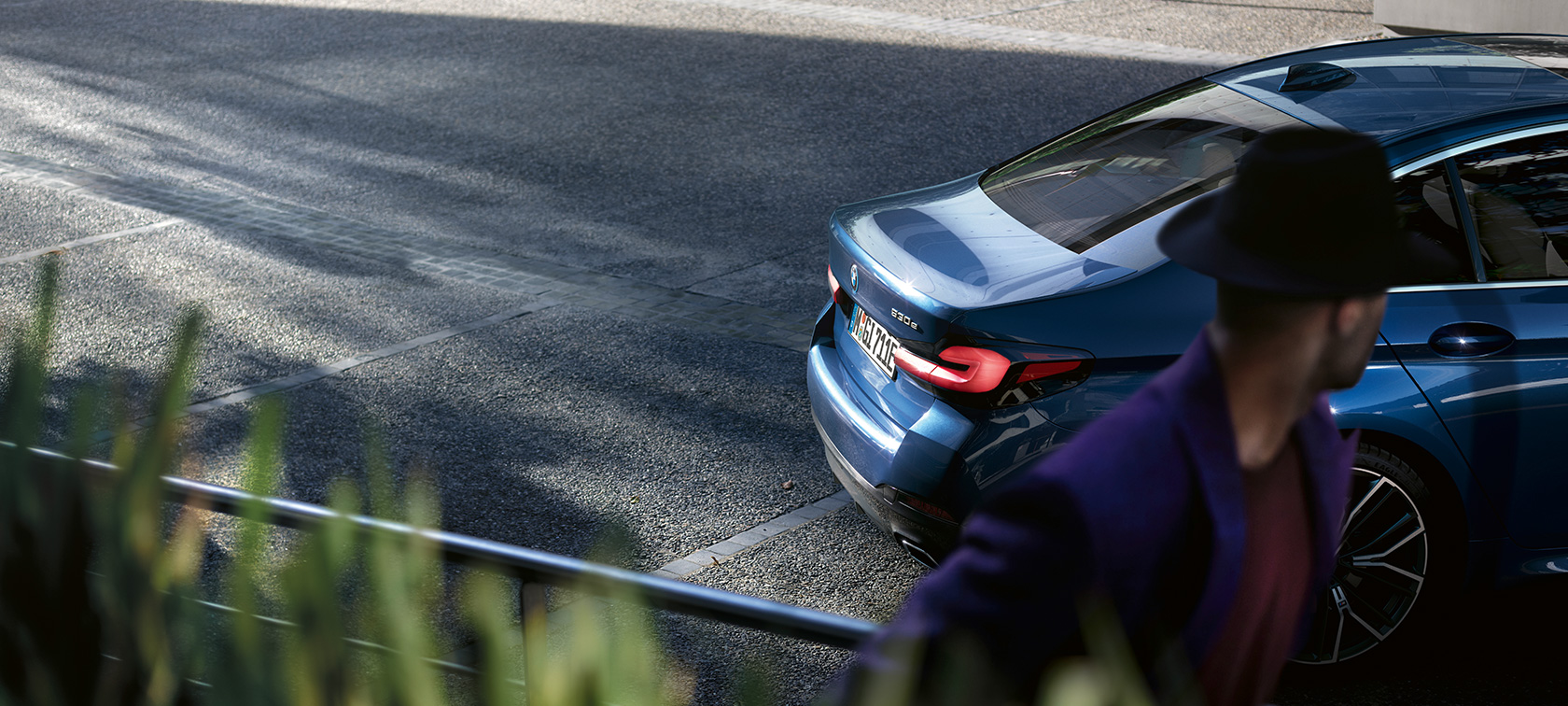 Vyras stovi prie besiparkuojančio BMW, BMW 5 serijos sedanas G30 BMW 5 serijos sedanas G30 Facelift 2020 vyras stovi prie besiparkuojančio BMW