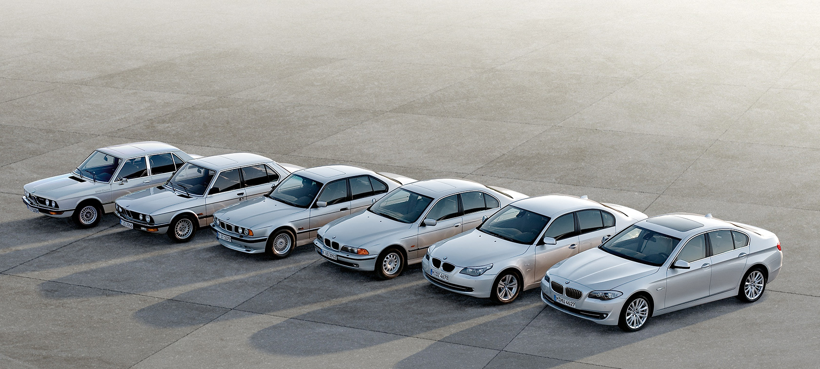BMW 5 serijos sedanas, 6 kartų modeliai stovintys greta BMW 5 serijos sedanas, 6 kartų modeliai stovintys greta
