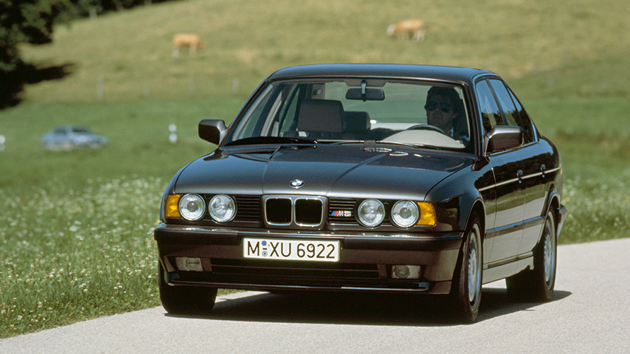 BMW M sedanas (E34) važiuojančio automobilio trijų ketvirčių vaizdas iš priekio BMW M sedanas (E34) važiuojančio automobilio trijų ketvirčių vaizdas iš priekio