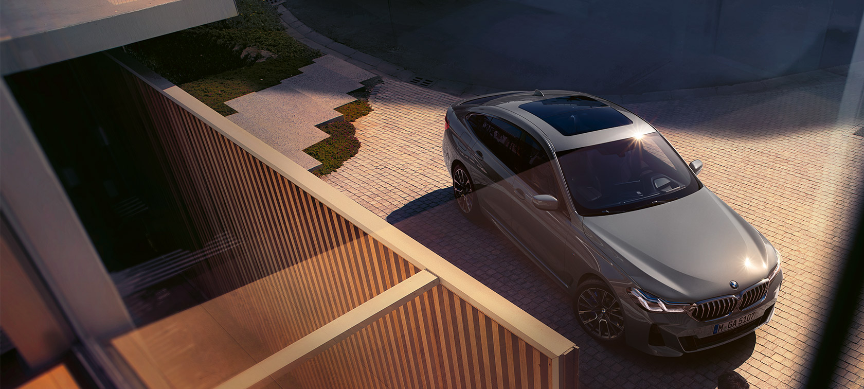 BMW 6 serijos Gran Turismo 640i xDrive (G32) pilkos Bernina Grey spalvos BMW 6 serijos Gran Turismo 640i xDrive (G32), pilkos Bernina Grey spalvos, trijų ketvirčių vaizdas iš priekio pastato fone
