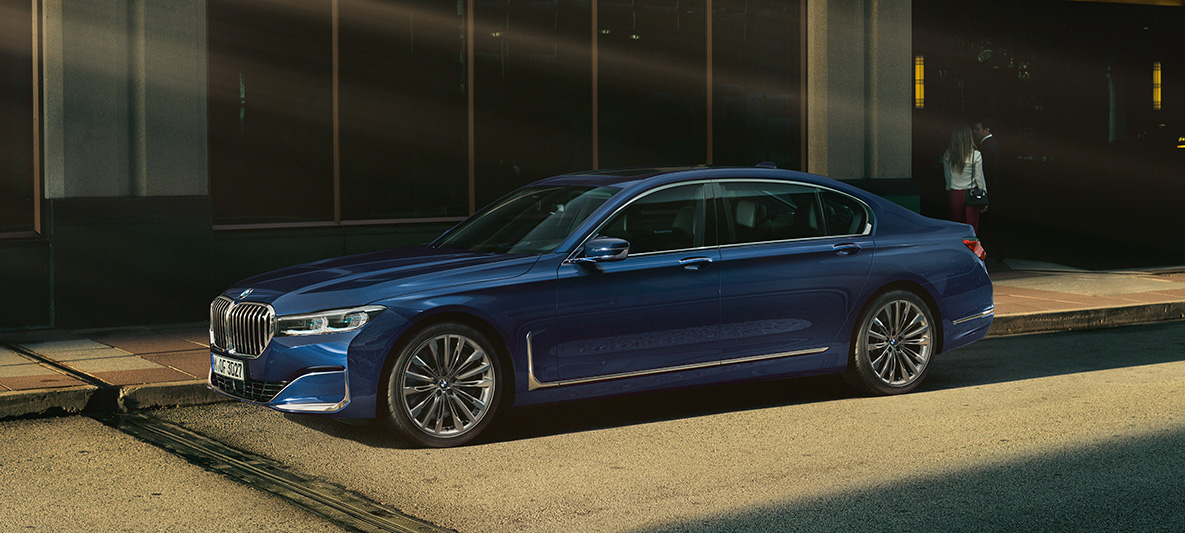 BMW 7 serijos sedanas (G11 G12) BMW Individual raudonos Aventurine Red metalizuotos kėbulo spalvos, vaizdas iš šono BMW 7 serijos sedanas (G11 G12) BMW Individual raudonos Aventurine Red metalizuotos kėbulo spalvos, vaizdas iš šono miesto fone