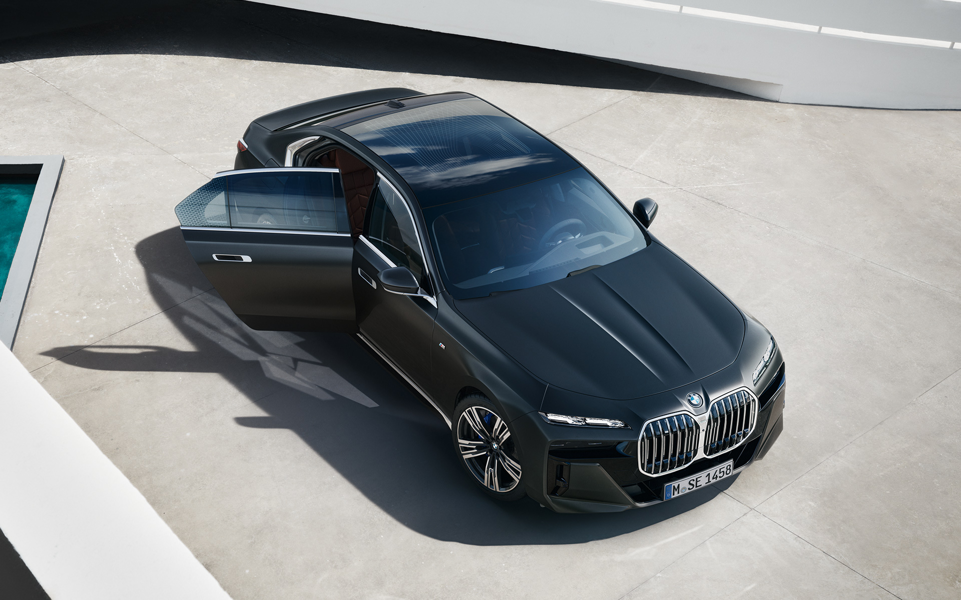 Vaizdas iš paukščio skrydžio BMW 7 serijos sedanas G70 ICE 740i M sport paketas pilkos metalizuotos Frozen Deep grey spalvos BMW 7 serijos sedanas G70 ICE 740i M sport paketas pilkos metalizuotos Frozen Deep grey spalvos vaizdas iš paukščio skrydžio su atidarytomis keleivio durelėmis