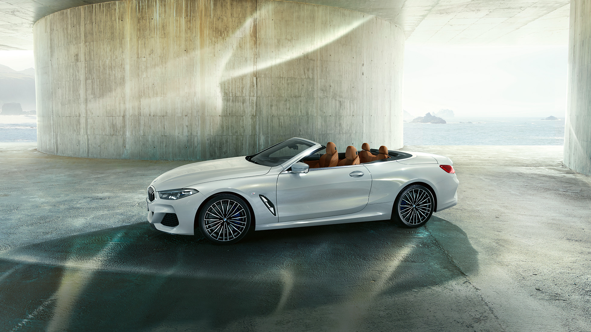 BMW M850i xDrive „Mineral White“ balto metaliko spalvos, vaizdas iš šono su atviru minkštu stogu. BMW M850i xDrive „Mineral White“ balto metaliko spalvos, vaizdas iš šono su atviru minkštu stogu.