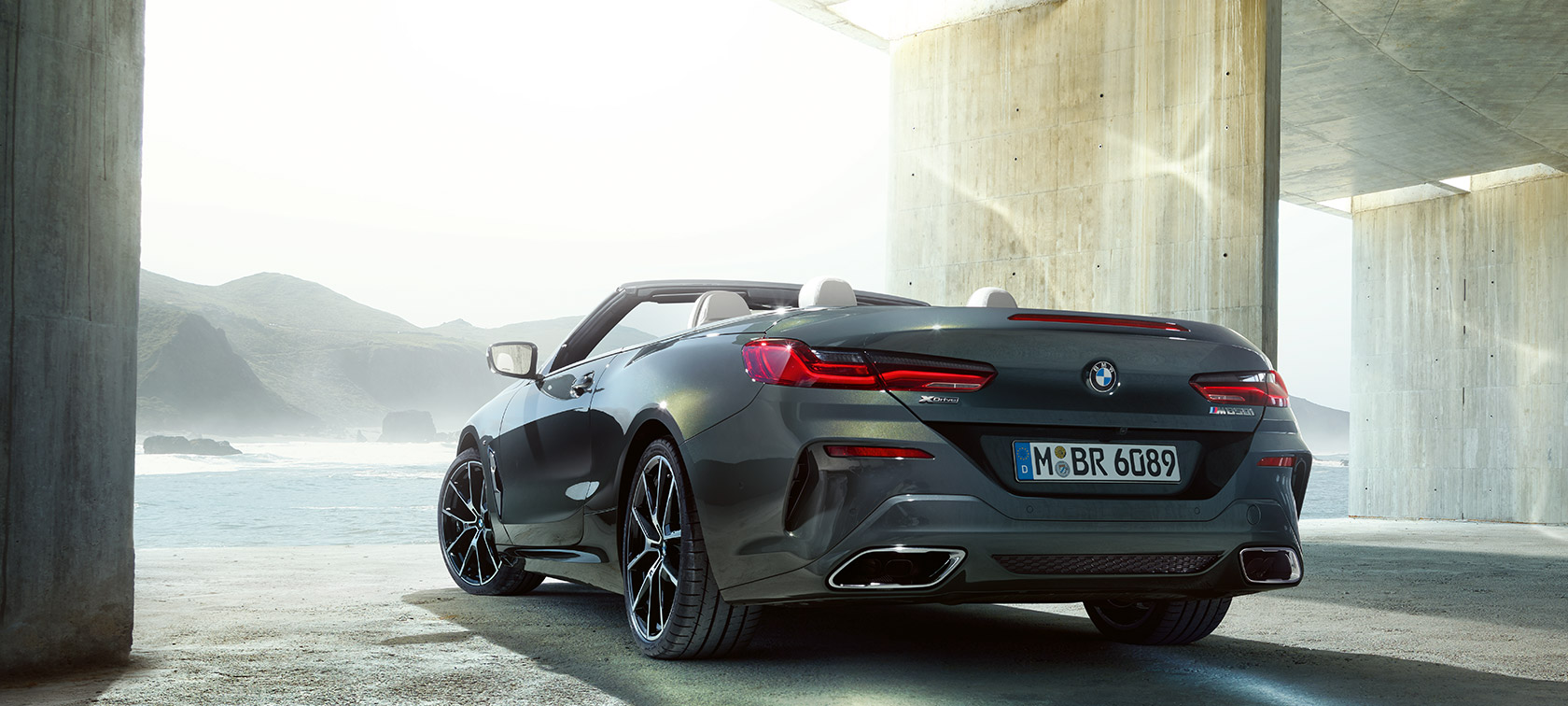 BMW M850i xDrive „Dravit Grey“ pilko metaliko spalvos, trijų ketvirčių vaizdas iš automobilio galo kairės BMW M850i xDrive „Dravit Grey“ pilko metaliko spalvos, trijų ketvirčių vaizdas iš automobilio galo kairės