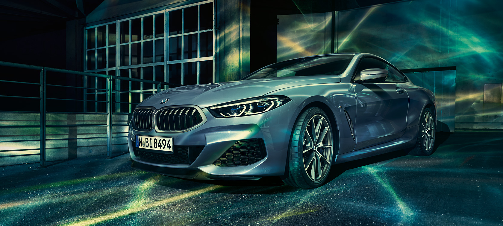 8 serijos BMW, važiuojantis keliu Naktinio miesto fone važiuojančio BMW 8 serijos Coupé nuotrauka.
