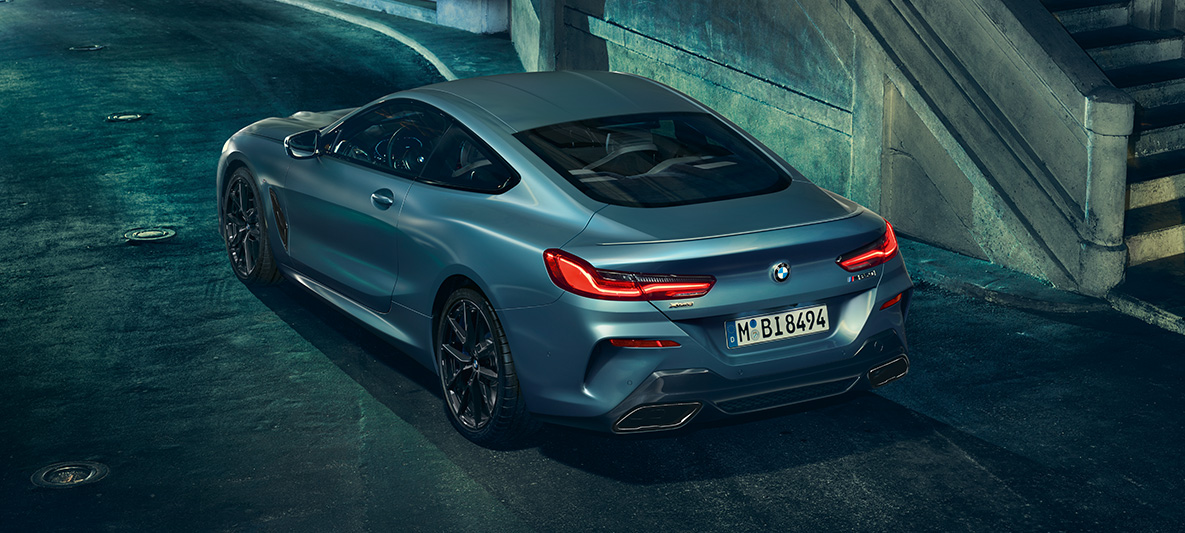 BMW M850i Coupé First Edition, trijų ketvirčių vaizdas iš galo Miesto fone stovinčio BMW M850i Coupé First Edition trijų ketvirčių vaizdas iš galo
