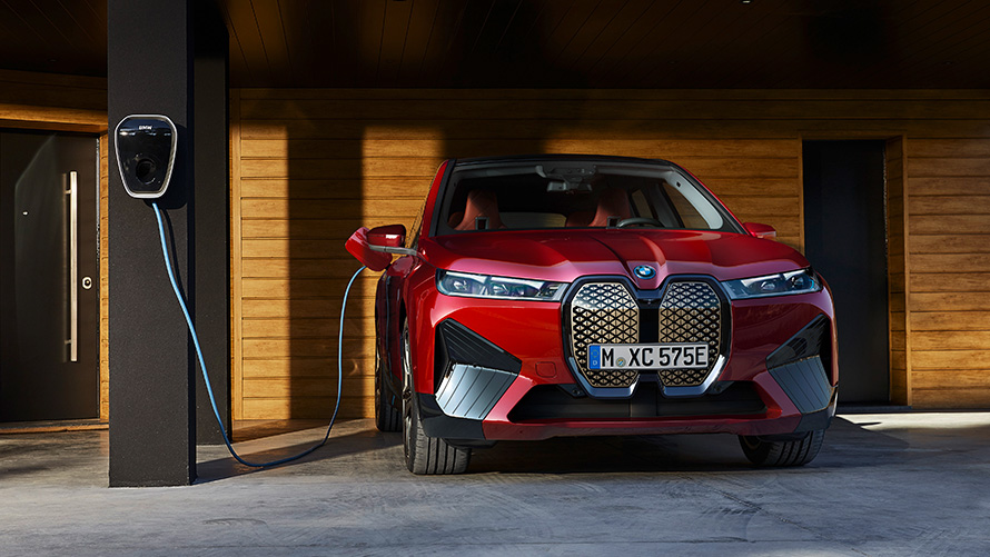 BMW iX i20 elektrinis SUV BMW iX xDrive50, įkrovimas 2021 m. elektrinis SUV BMW iX i20 automobilis, BMW Wallbox įkrovimo stotelėje kraunamas Aventurin Red spalvos BMW iX xDrive50 automobilis