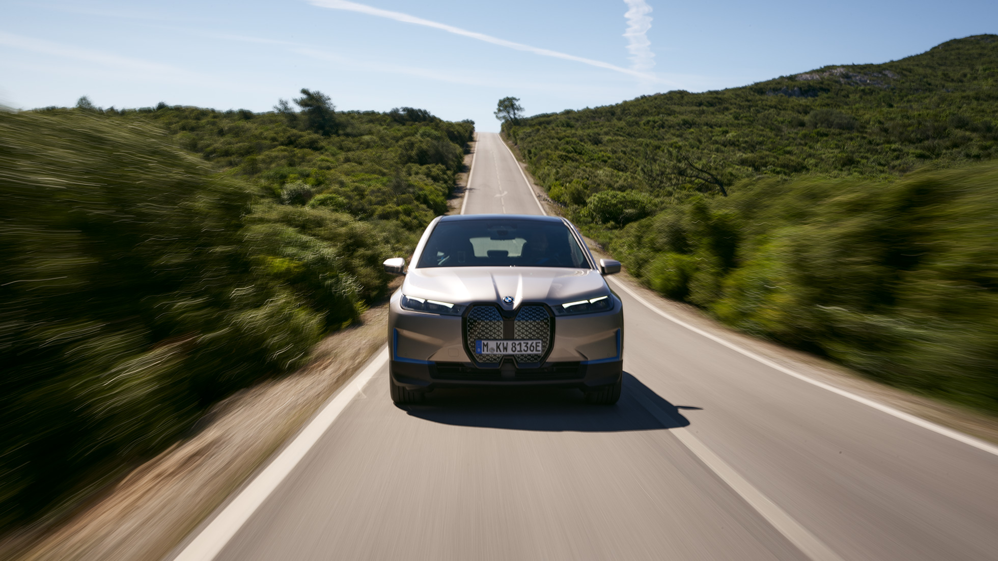 BMW iX keliu važiuojančio automobilio vaizdas iš priekio BMW iX sidabro Cashmere Silver spalvos keliu važiuojančio i20 vaizdas iš priekio