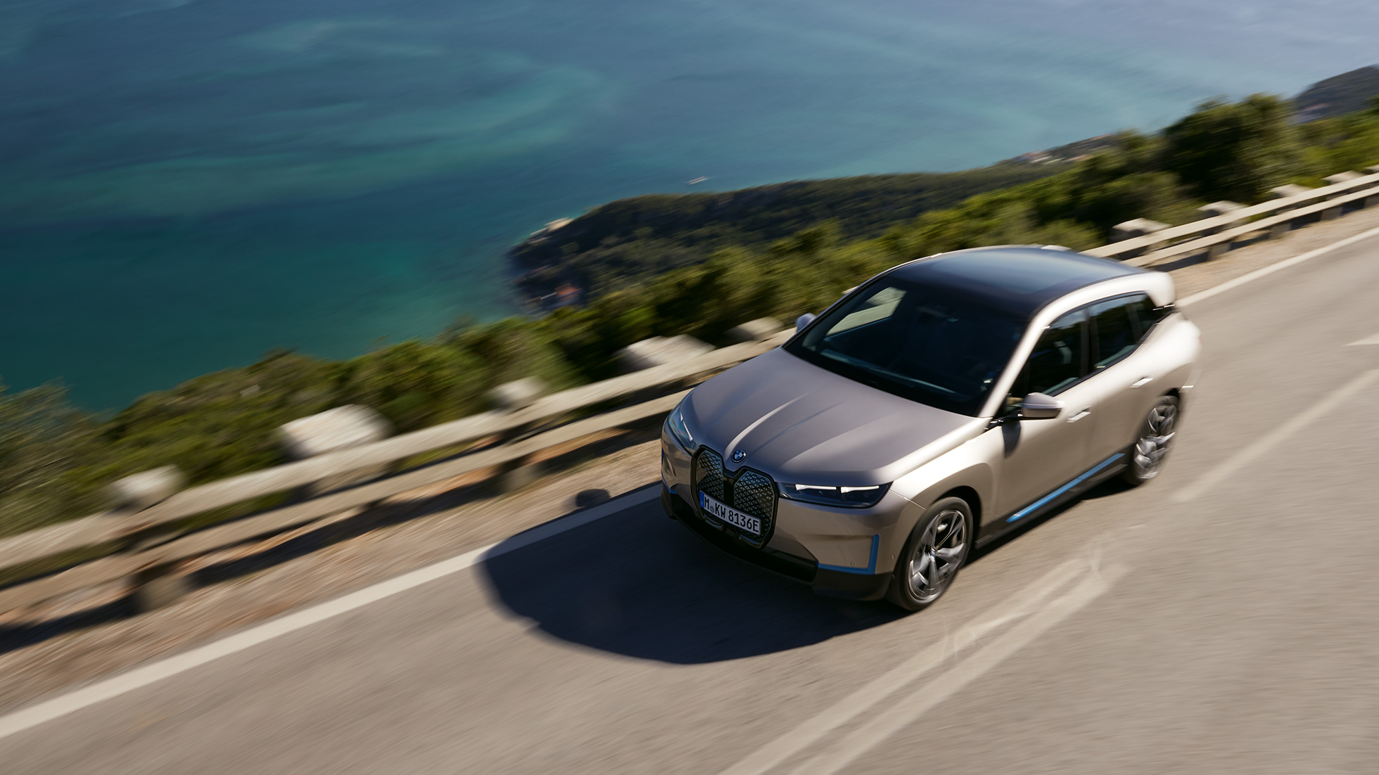 BMW iX keliu važiuojančio automobilio vaizdas iš paukščio skrydžio BMW iX sidabro Cashmere Silver spalvos keliu važiuojančio i20 vaizdas iš paukščio skrydžio