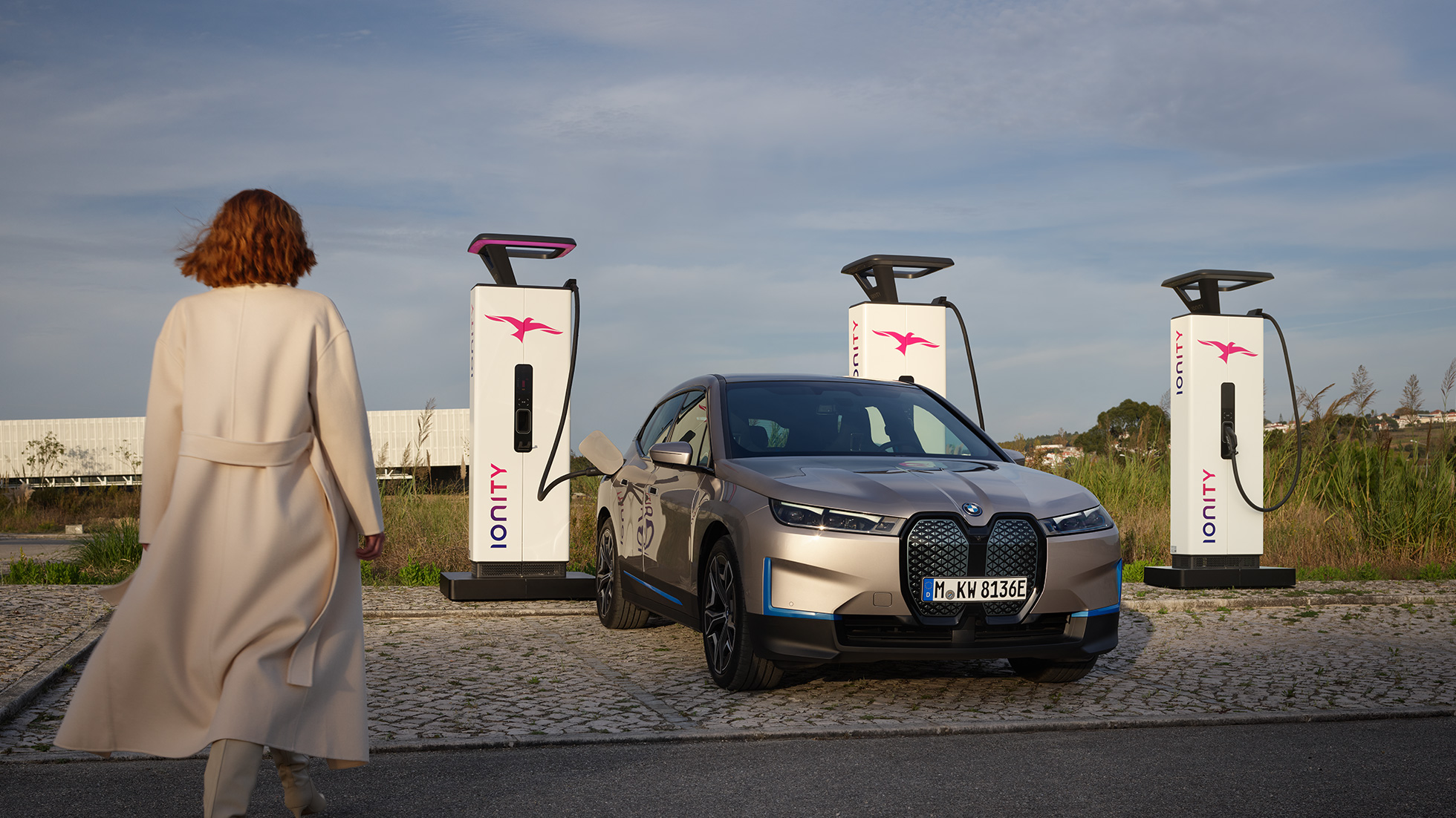 BMW iX trijų ketvirčių vaizdas iš priekio įkrovimo stotelėje BMW iX sidabro Cashmere Silver spalvos i20 trijų ketvirčių vaizdas iš priekio įkrovimo stotelėje