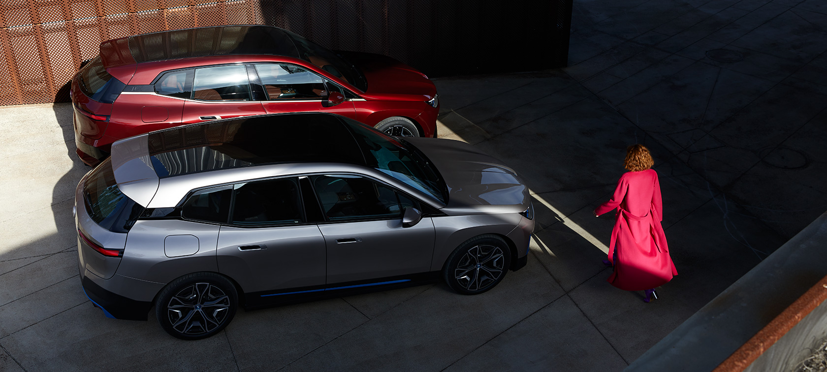 BMW iX vaizdas iš paukščio skrydžio su modeliu BMW iX raudonos Aventurin Red spalvos ir sidabro Cashmere Silver spalvos i20 vaizdas iš paukščio skrydžio su modeliu