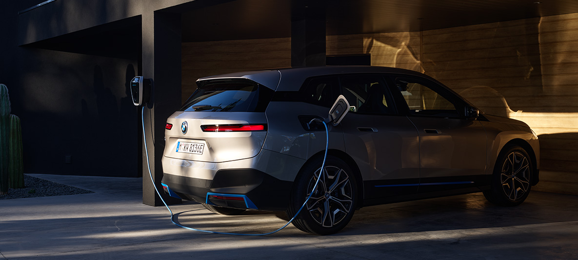 BMW iX įkraunamo BMW Wallbox automobilio trijų ketvirčių vaizdas iš galo BMW iX sidabro Cashmere Silver spalvos i20 įkraunamo BMW Wallbox automobilio trijų ketvirčių vaizdas iš galo
