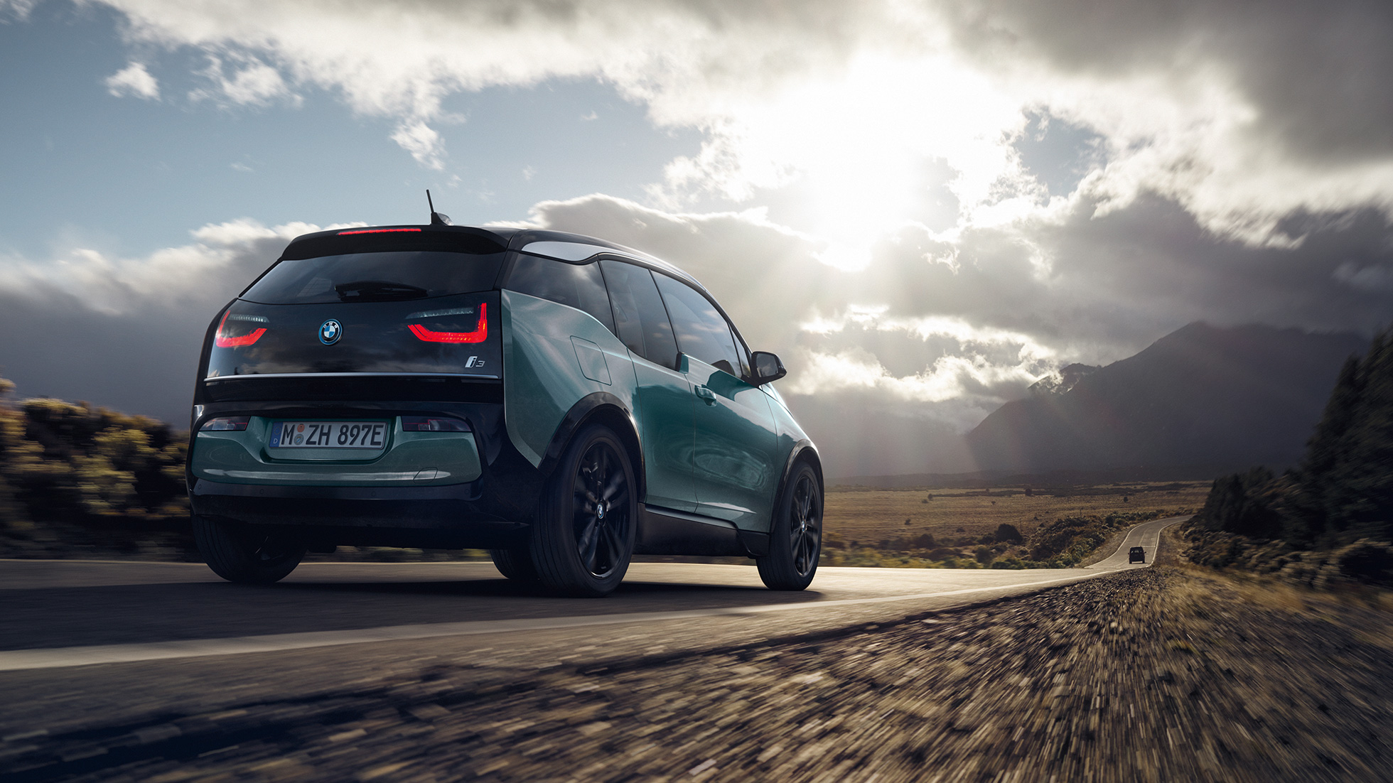 BMW i3 2018 trijų ketvirčių greitkeliu važiuojančio automobilio vaizdas iš galo BMW i3 I01 2018 Jucaro beige smėlio spalvos su Frozen Grey pilko metaliko spalvos akcentu, trijų ketvirčių greitkeliu važiuojančio automobilio vaizdas iš galo