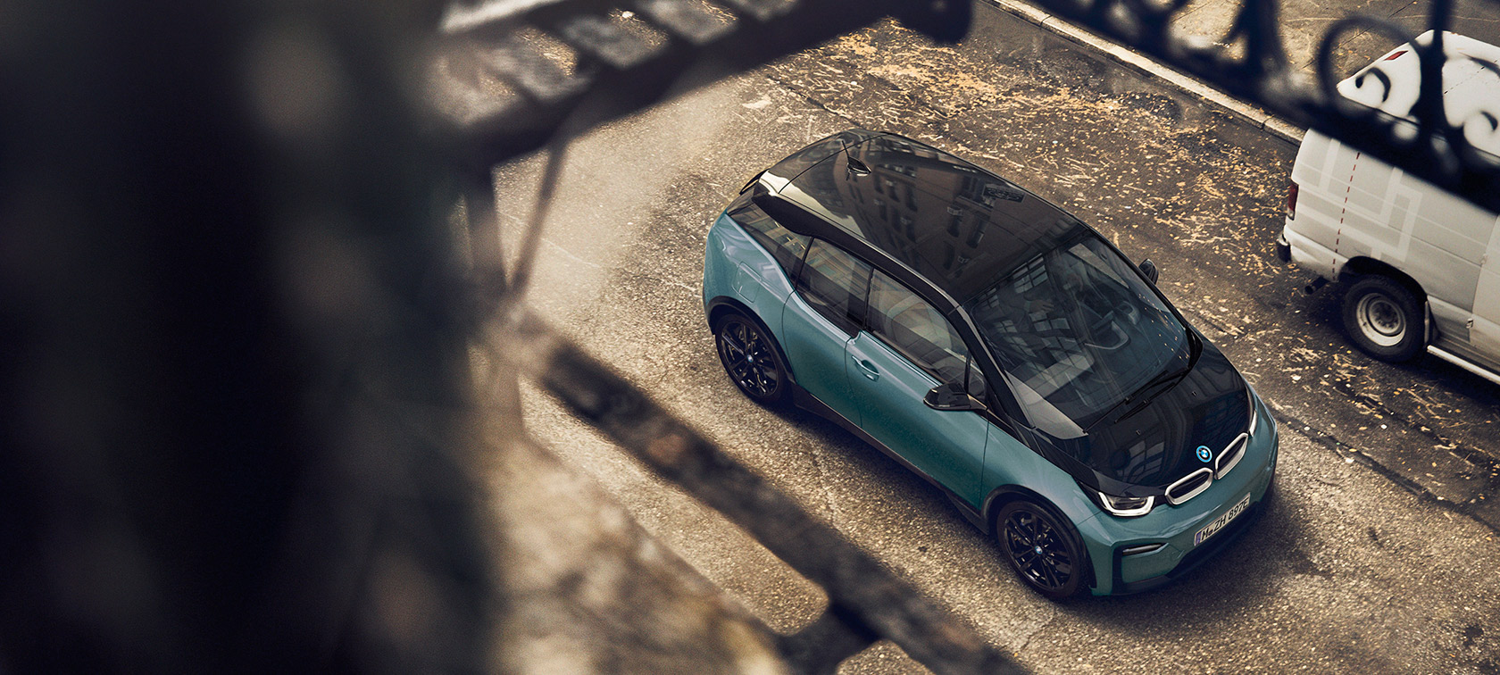 BMW i3 (I01) 2018 vaizdas iš paukščio skrydžio BMW i3 (I01) 2018 mėlynos <i>Blue Ridge Mountain</i> spalvos su pilku metalizuotu <i>Frozen Grey</i> apdailos akcentu, vaizdas iš paukščio skrydžio, anglies pluošto stogas