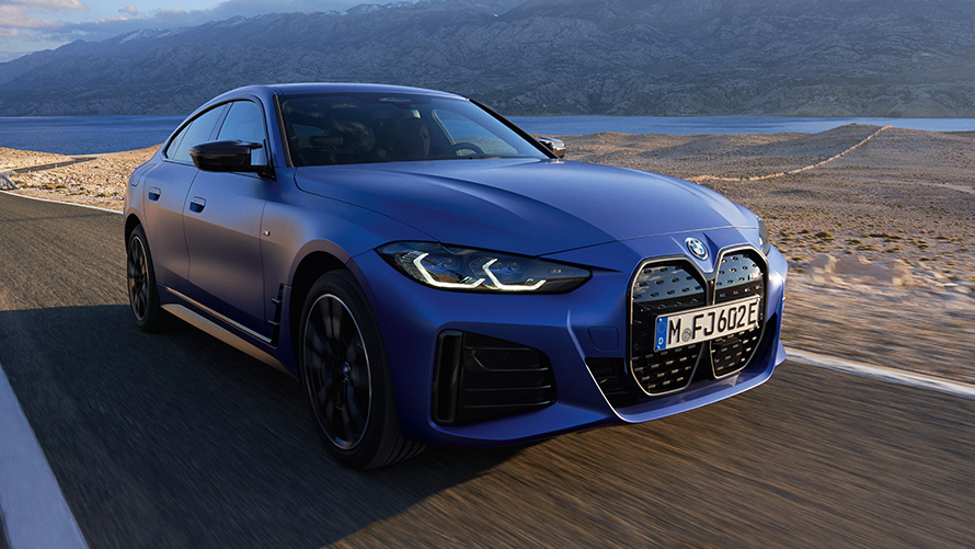Trijų ketvirčių vaizdas iš priekio,BMW i4 M50 (G26) 2021 BMW i4 M50 (G26) 2021 M mėlynos metalizuotos Portimao Blue kėbulo spalvos, keliu važiuojančio automobilio trijų ketvirčių vaizdas iš priekio