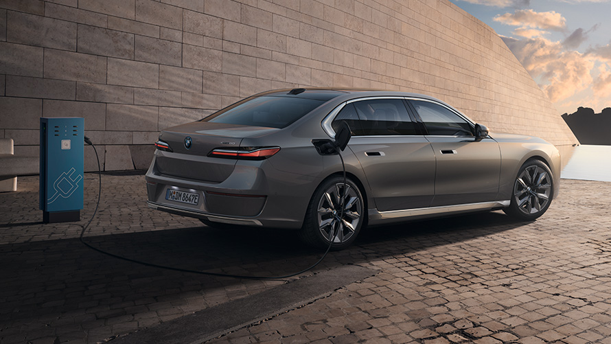 BMW i7 sedanas G70 3/4 šoninis vaizdas iš galo BMW i7 sedanas G70 BMW Individual pilkos metalizuotos Oxid grey spalvos 3/4 šoninis vaizdas iš galo įkrovimo stotelėje