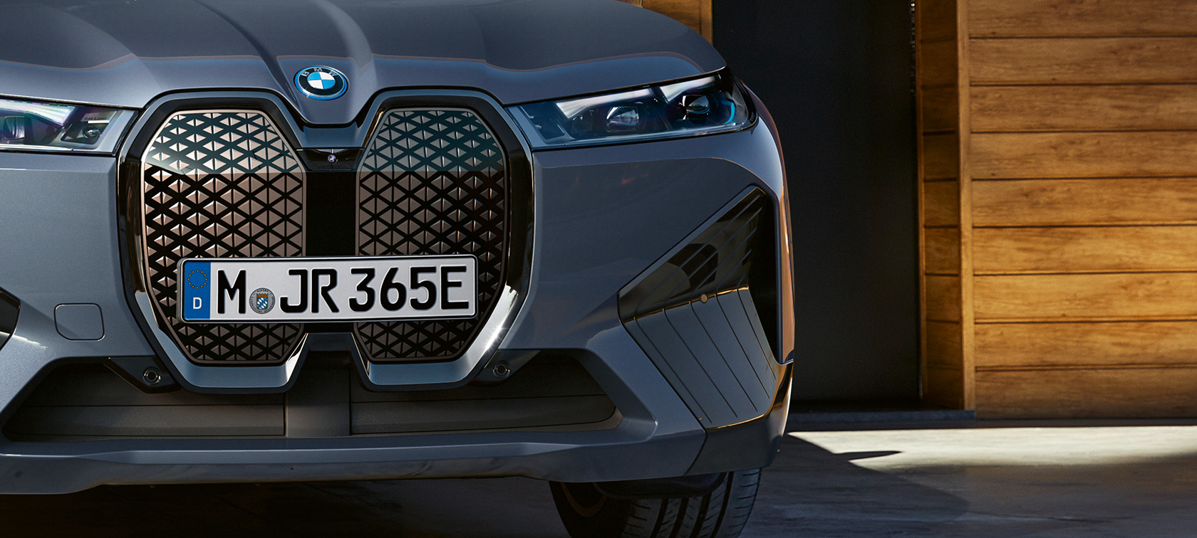 iX M60 i20 2022 elektrinis SUV elektromobilis pilkos BMW Individual Storm Bay metalizuotos kėbulo spalvos vaizdas iš priekio su vertikaliomis BMW priekinėmis grotelėmis