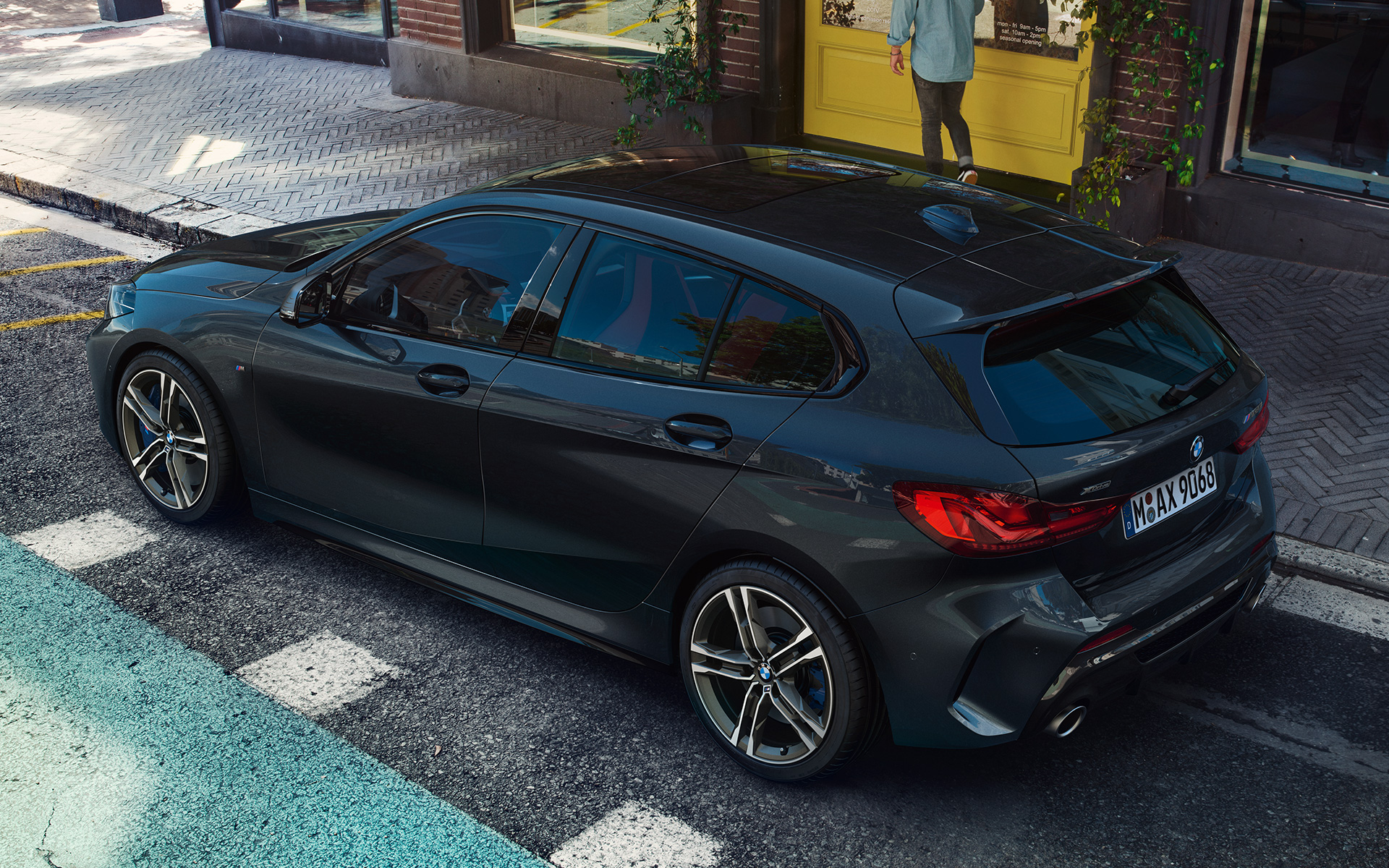 BMW M135i xDrive (F40), juodos metalizuotos Black Sapphire spalvos, parkuojamo automobilio šoninis vaizdas iš paukščio skrydžio