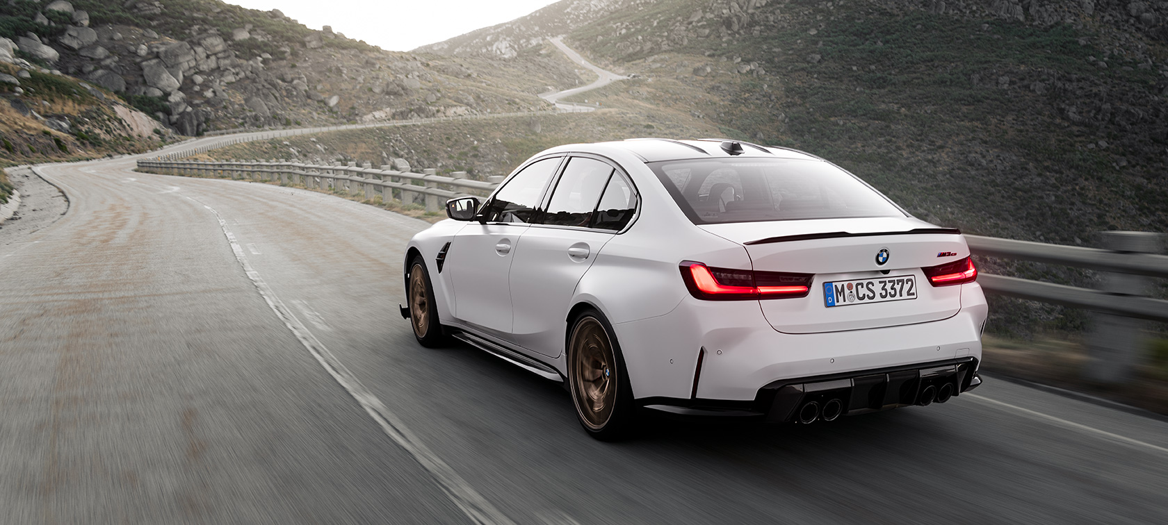 BMW M3 CS G80 važiuojančio automobilio trijų ketvirčių vaizdas iš galo BMW M3 CS G80 kalnų keliu važiuojančio automobilio trijų ketvirčių vaizdas iš galo