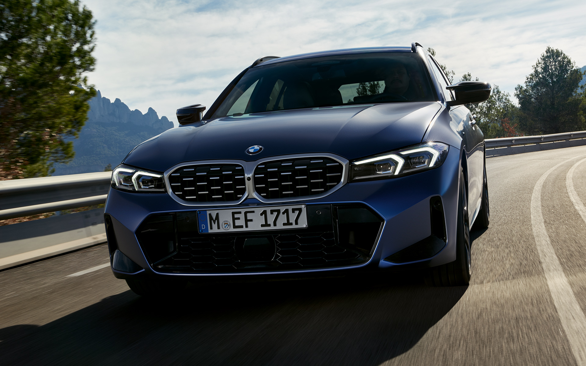 Gatve važiuojančio BMW M340i xDrive Touring G21 vaizdas iš priekio Gatve važiuojančio BMW M340i xDrive Touring G21 mėlynos Frozen Tanzanite Blue spalvos vaizdas iš priekio